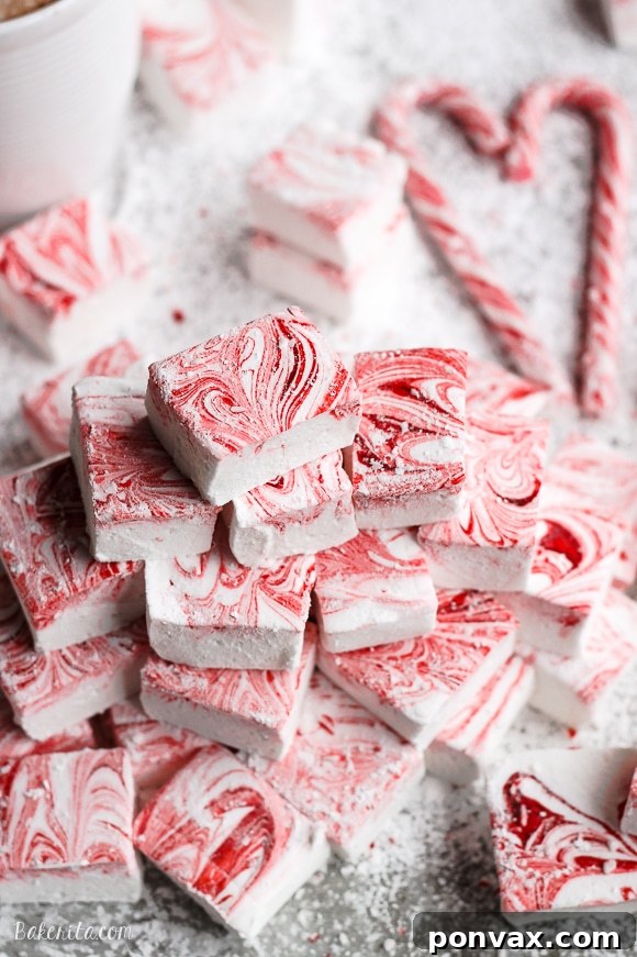 Candy Cane Cloud Bites 2 Close-up of fluffy homemade Peppermint Marshmallows with a vibrant red swirl, dusted with powdered sugar, ready to be enjoyed in hot cocoa or as a festive holiday treat.