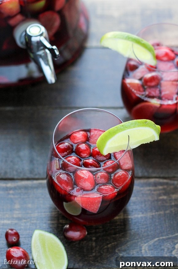 Tangy Cranberry Lime Sangria 6 Serving a glass of sparkling Cranberry Lime Sangria with ice, cranberries, and lime slices.
