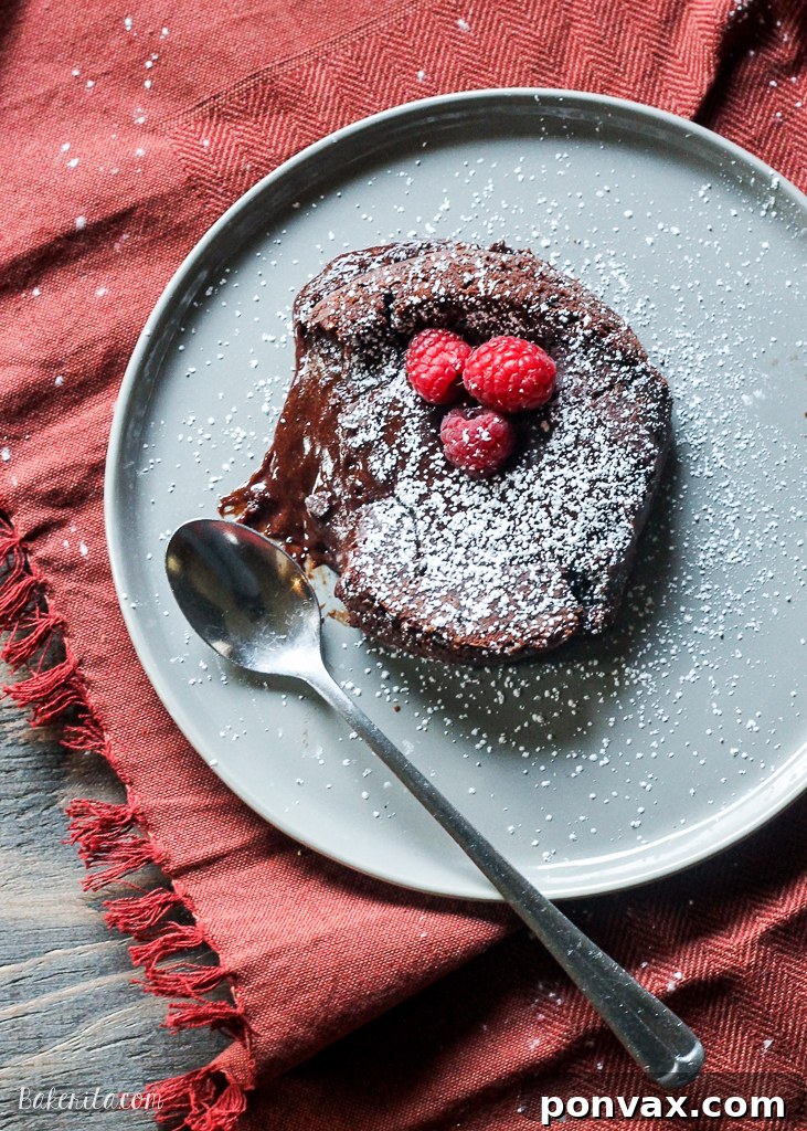 Two individual Easy Chocolate Lava Cakes, perfectly baked with a glossy exterior and a visibly molten chocolate center, garnished with a dusting of powdered sugar.