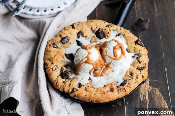 A close-up shot of a warm, golden-brown Peanut Butter Chocolate Chip Skillet Cookie, freshly baked in a cast iron skillet, with melted chocolate and a dollop of peanut butter visible.