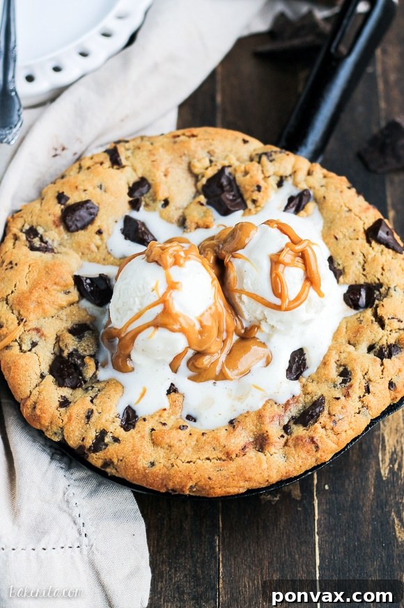 A close-up of a Peanut Butter Chocolate Chip Skillet Cookie with a scoop of melting vanilla ice cream on top, showing the rich, gooey interior.