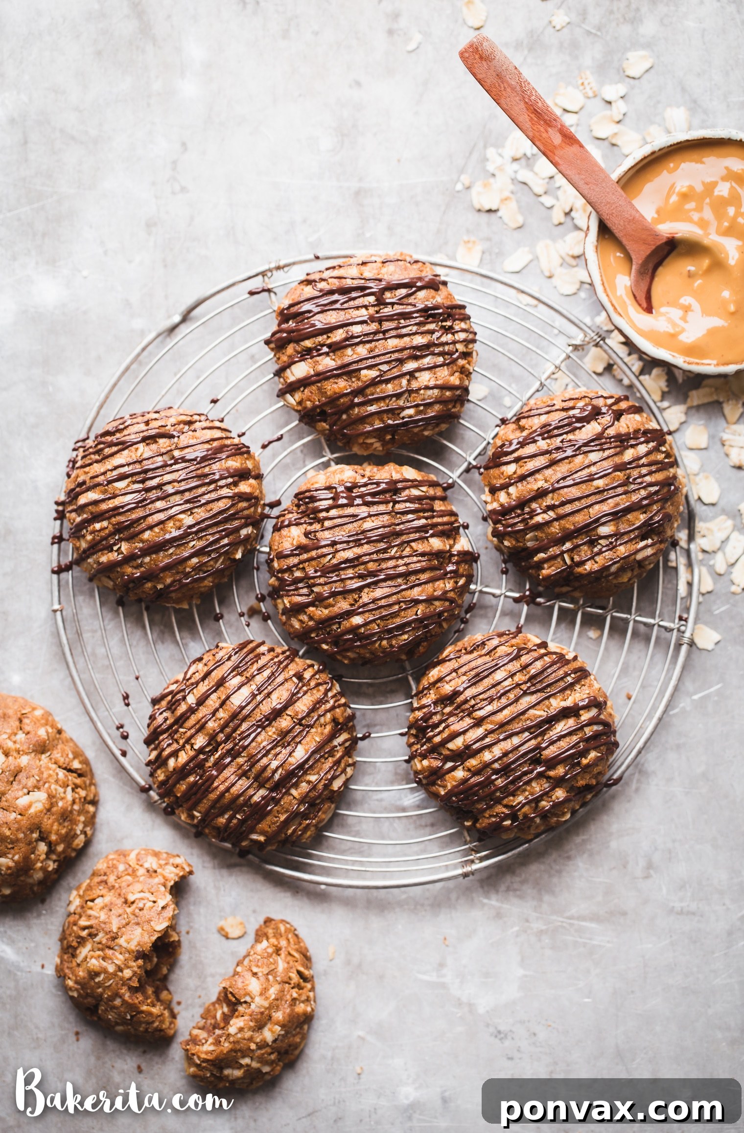 A collection of Peanut Butter Oatmeal Cookies, some beautifully drizzled with dark chocolate, alongside a small bowl of creamy peanut butter in the corner, highlighting the irresistible combination of flavors.