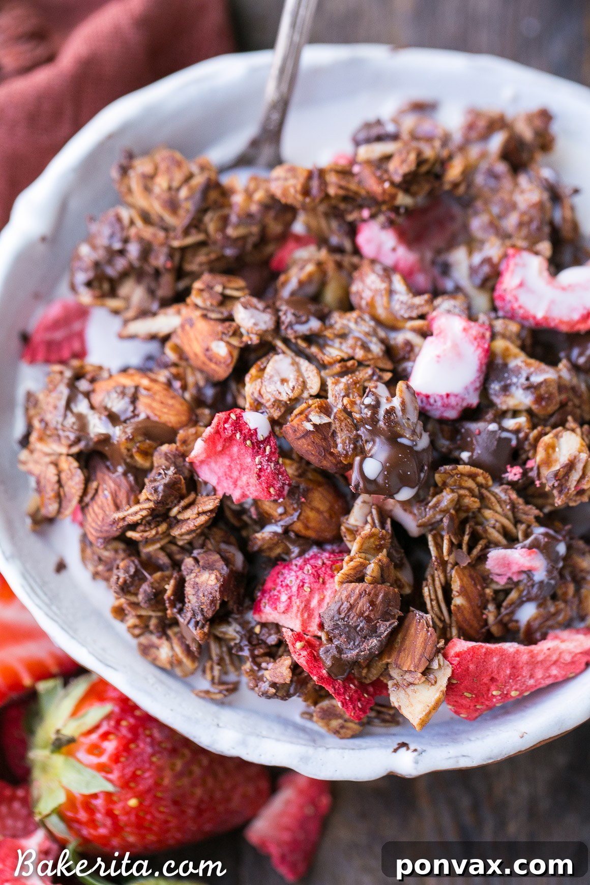 A bowl of Chocolate Strawberry Granola with freeze-dried strawberries and a spoon