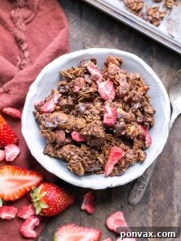A bowl of Chocolate Strawberry Granola with milk and fresh berries