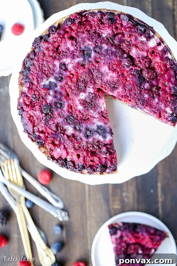A beautifully inverted Berry Upside Down Cake, showcasing the rich, vibrant colors of raspberries, blackberries, and blueberries on top, with a golden-brown cake layer and hints of cinnamon crumb.