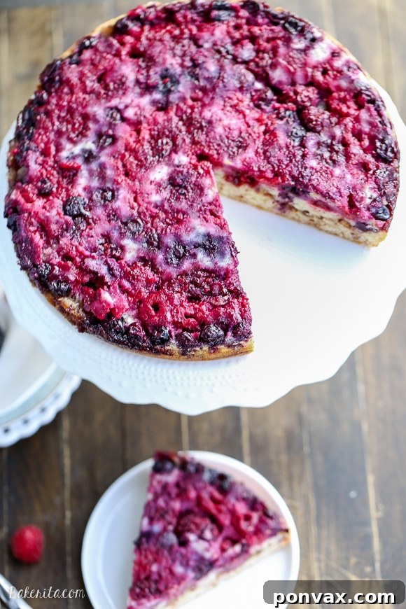 Close-up shot of the Berry Upside Down Cake, showing the glistening, juicy berries and the moist cake texture, with a glimpse of the cinnamon swirl layer.