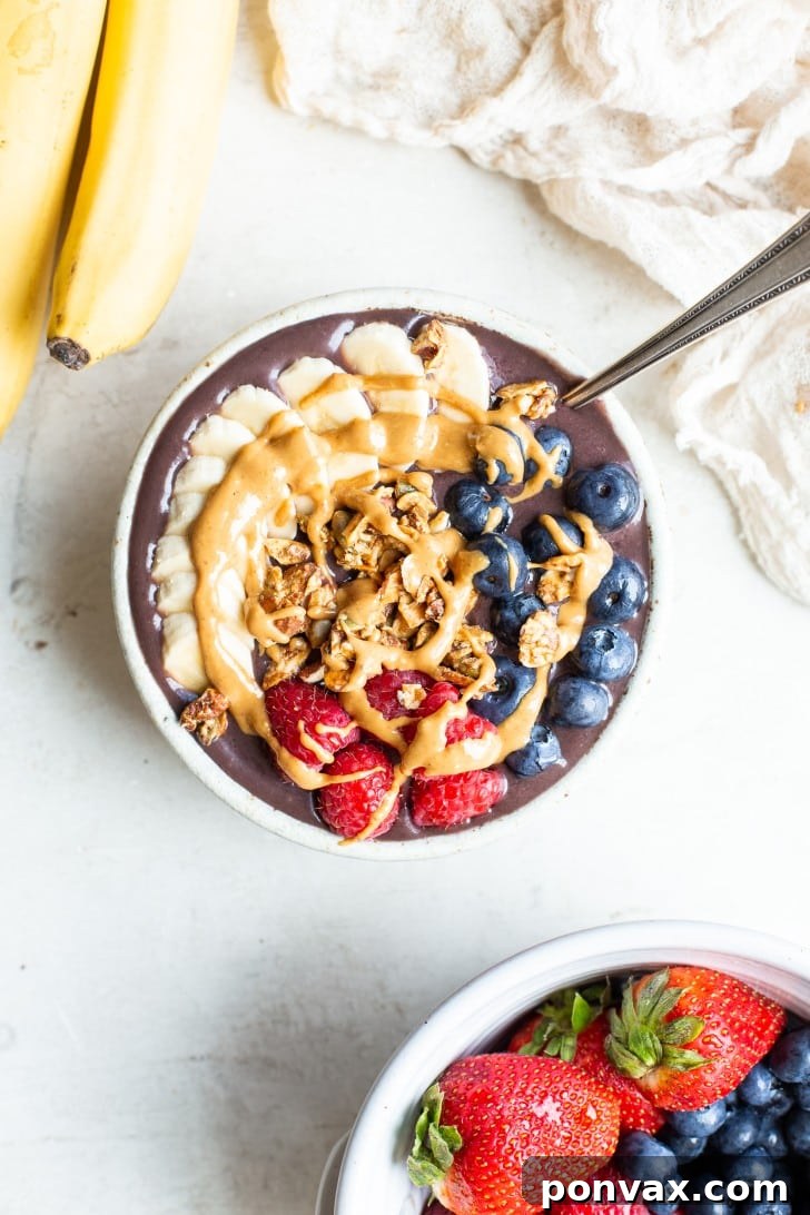 A vibrant homemade acai bowl topped with fresh berries, sliced banana, and granola, photographed from above.