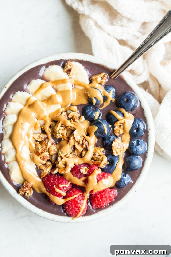 A close-up of a homemade acai bowl with a creamy texture, garnished with various fresh fruits and seeds.