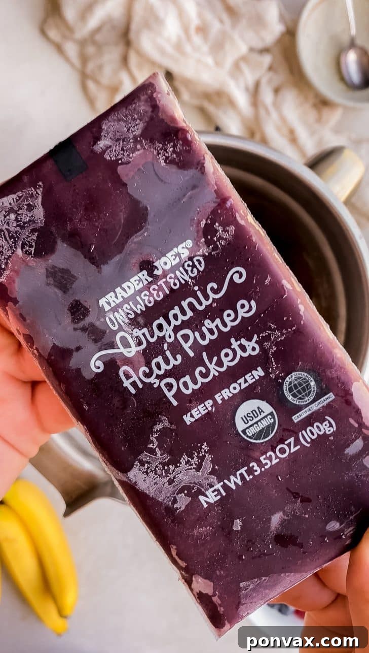 A high-angle shot of a blender with frozen acai, banana, and non-dairy milk being blended.