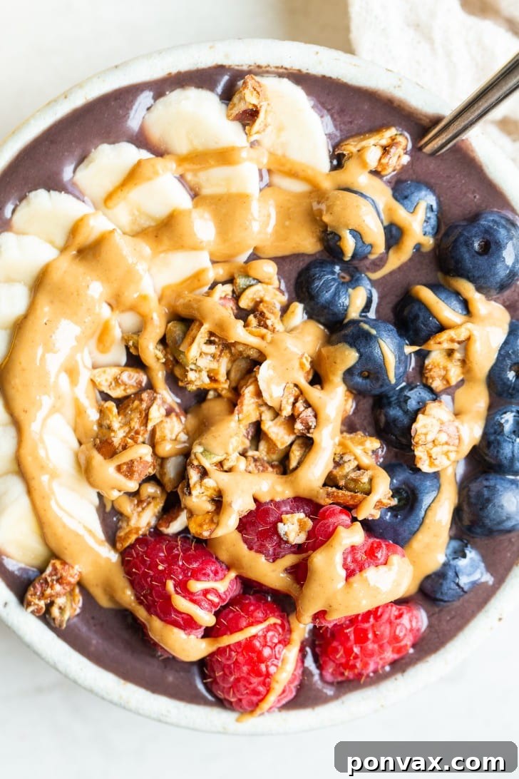 A beautifully plated acai bowl overflowing with colorful toppings, including various fruits, nuts, and seeds.