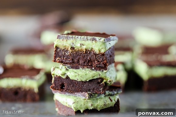 Close-up of a square of Mint Chocolate Chip Brownie, showing the distinct fudgy chocolate base, creamy mint layer with chocolate chips, and a glossy chocolate topping.