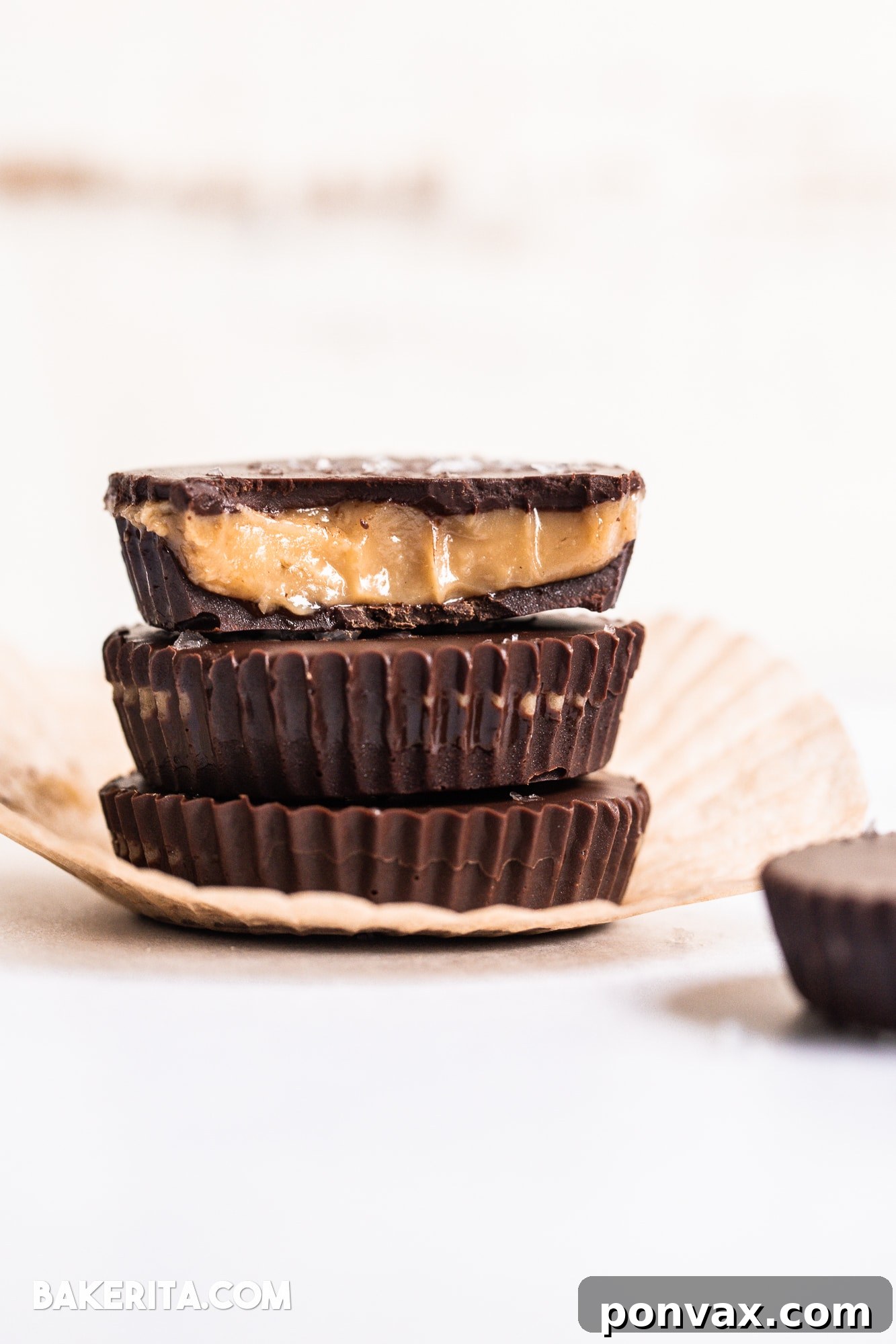 Delicious Vegan Chocolate Peanut Butter Caramel Cups in mini muffin liners, showcasing a rich chocolate exterior and a creamy filling.
