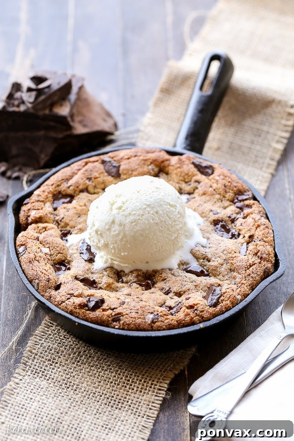 Warm Paleo Skillet Chocolate Chip Dream 2 A warm Paleo Chocolate Chip Skillet Cookie, golden brown with melted dark chocolate chunks and a soft, gooey center, presented in a cast iron skillet.
