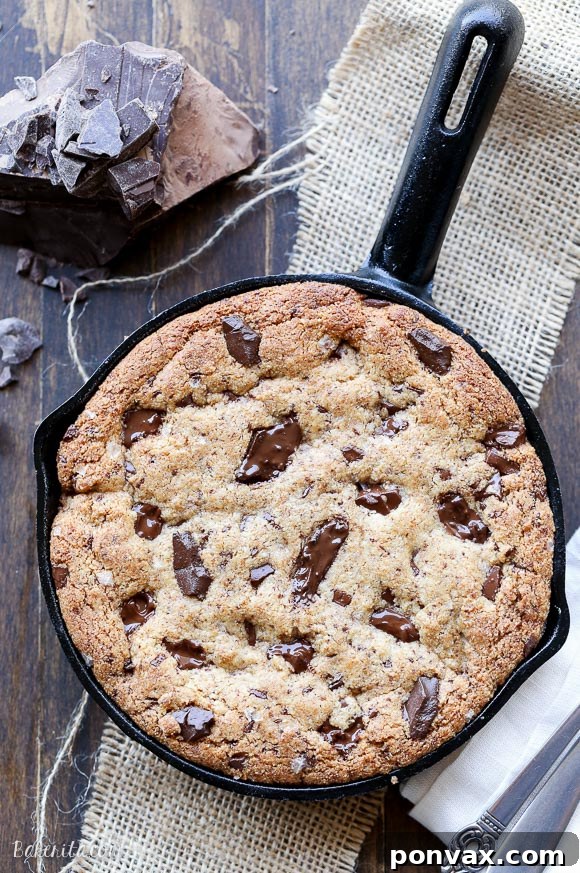 Warm Paleo Skillet Chocolate Chip Dream 3 A spoon digging into the soft, gooey center of a Paleo Skillet Cookie, revealing its rich texture and melted chocolate.