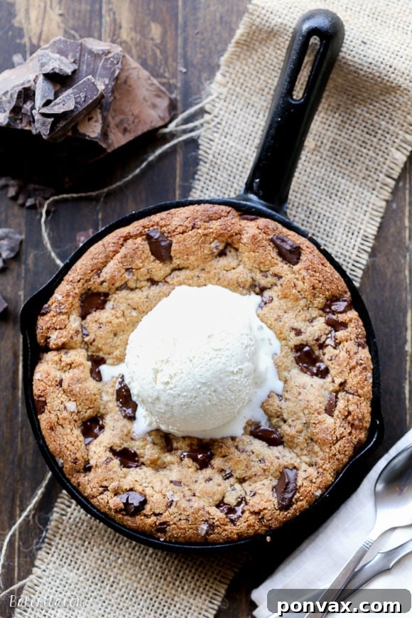 Warm Paleo Skillet Chocolate Chip Dream 5 An overhead view of a baked Paleo Skillet Cookie, still in the pan, sprinkled with flaky sea salt and featuring generous dark chocolate chunks.