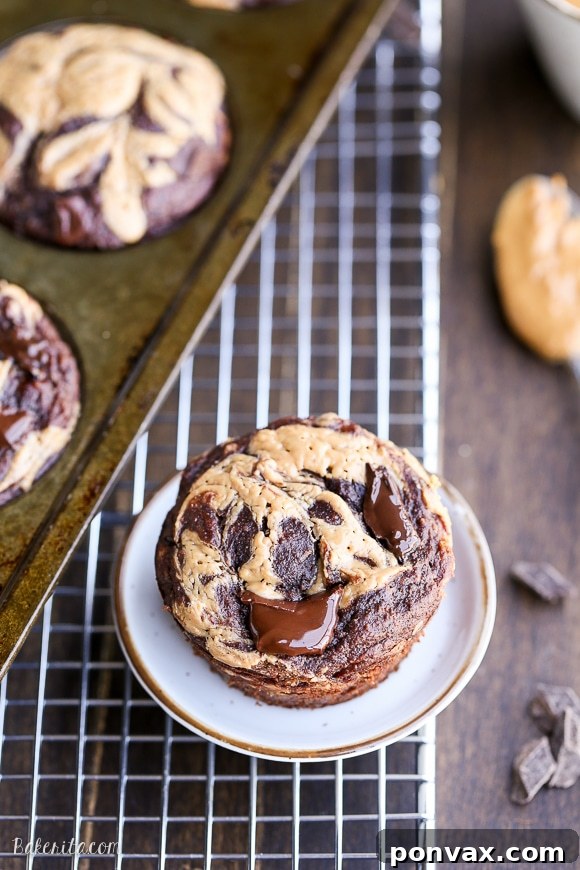 A batch of warm Chocolate Peanut Butter Banana Muffins cooling on a rack, with a delightful peanut butter swirl on top.