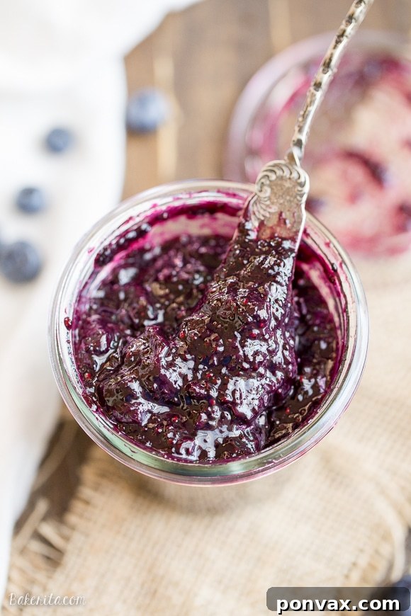 A close-up of a spoonful of homemade blueberry chia jam, highlighting the tiny chia seeds and the glossy fruit pieces.