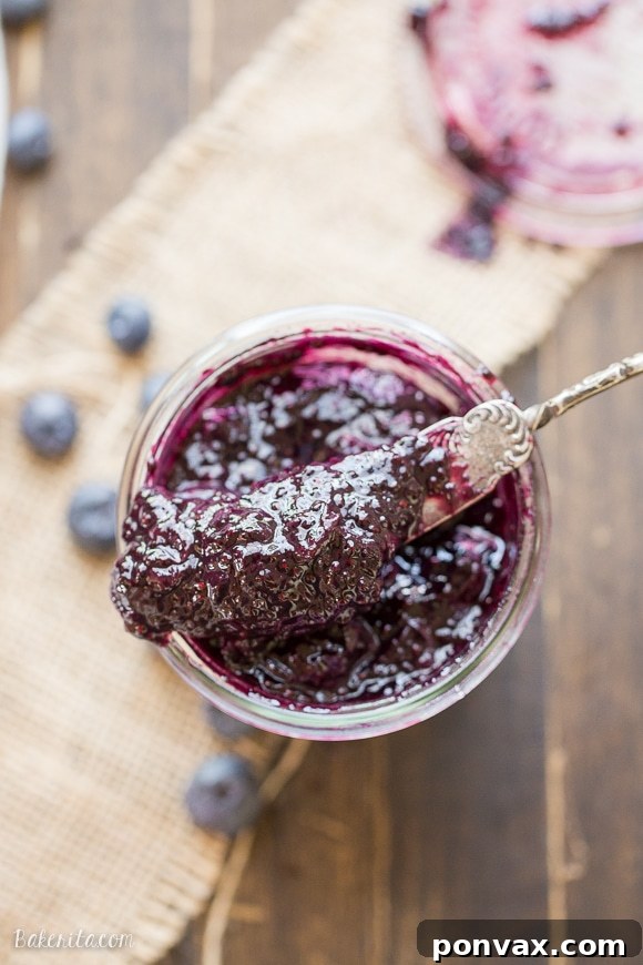 Two jars of freshly made blueberry chia jam, ready for storage or immediate enjoyment on a rustic wooden surface.