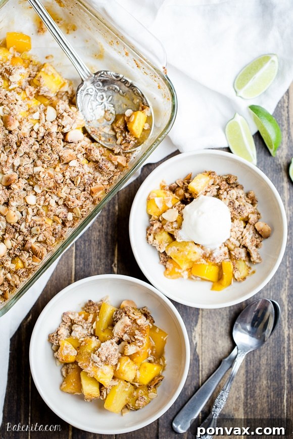 A top-down view of the irresistible Mango Pineapple Crumble with its golden coconut macadamia nut topping, hinting at the sweet, tangy tropical fruit beneath. This gluten-free, vegan, and refined sugar-free dessert is a true taste of paradise.