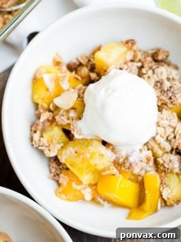 A vibrant close-up of the baked Mango Pineapple Crumble, showcasing its golden, crisp topping and the glistening, sweet fruit filling. A perfect representation of a gluten-free and vegan tropical dessert.