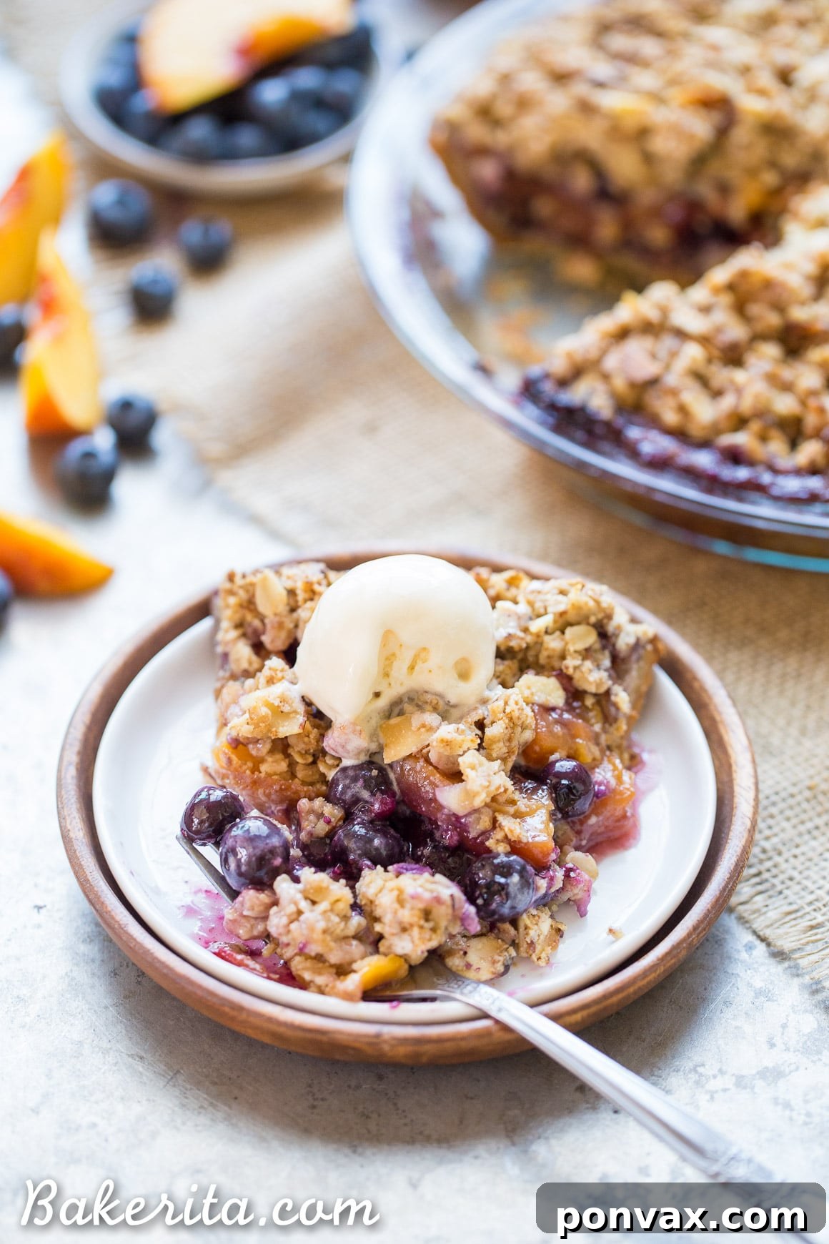 Sweet Freedom Blueberry Nectarine Almond Crumble Pie 6 A tempting slice of Gluten-Free Blueberry Nectarine Pie, revealing the fruit filling and sturdy almond flour crust, topped with a scoop of vanilla ice cream.