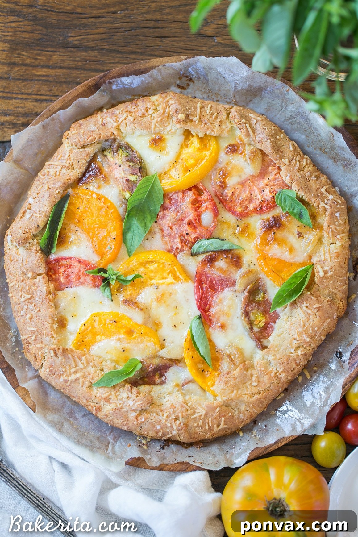 Rustic Gluten-Free Tomato Mozzarella Galette with a Golden Parmesan Crust 2 A beautifully rustic Mozzarella Heirloom Tomato Galette with a golden Parmesan crust, showcasing vibrant sliced heirloom tomatoes and melted mozzarella, garnished with fresh basil.