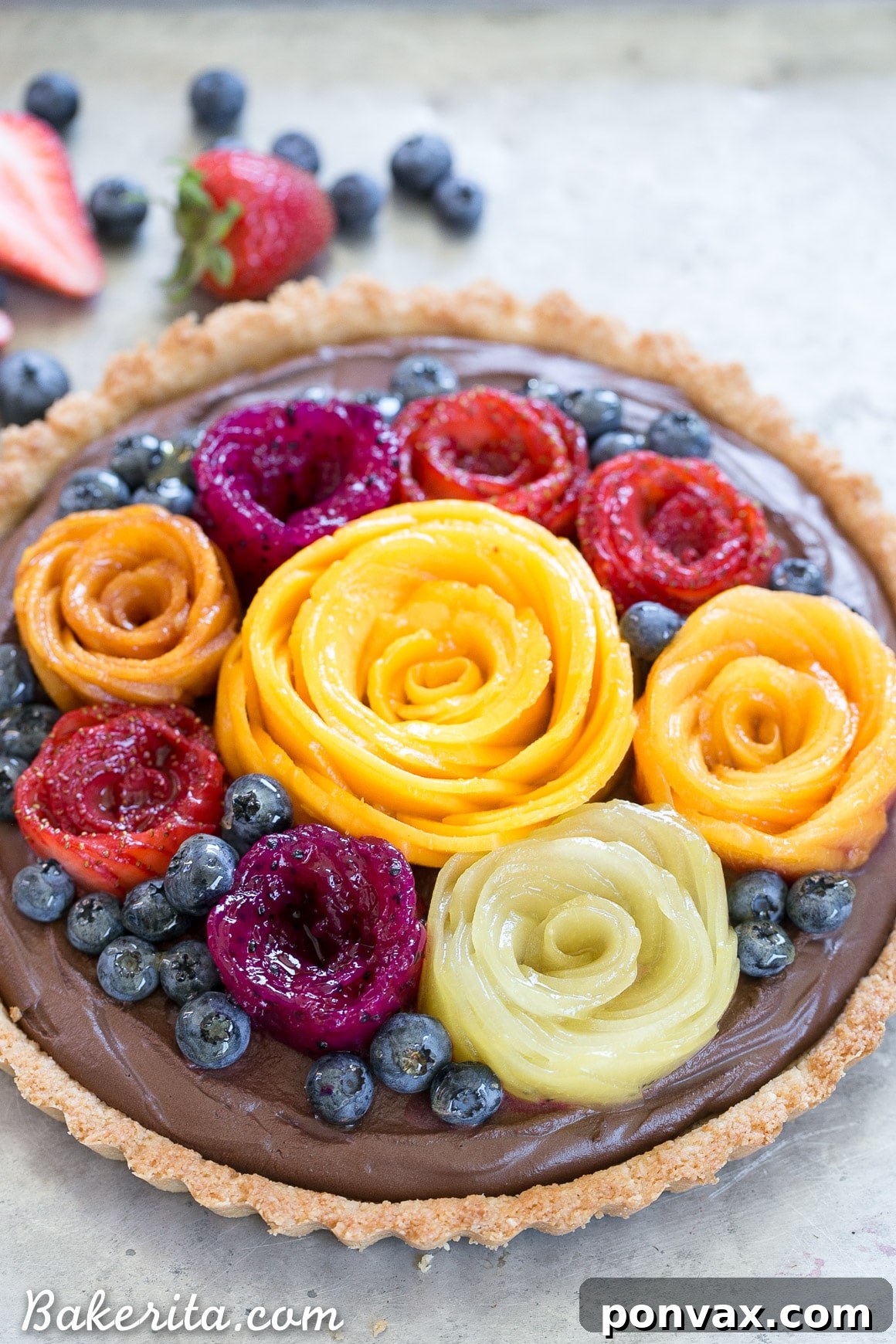 A vibrant display of Fresh Fruit Flowers on the Vegan Chocolate Mousse Tart. Strawberries, kiwi, and mango are meticulously arranged into beautiful floral designs, enhancing the dessert's visual appeal.