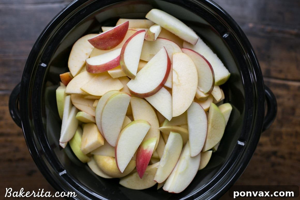 Naturally Sweet Slow Cooker Apple Butter 5 Sliced apples cooking in a slow cooker, starting to soften for homemade apple butter.