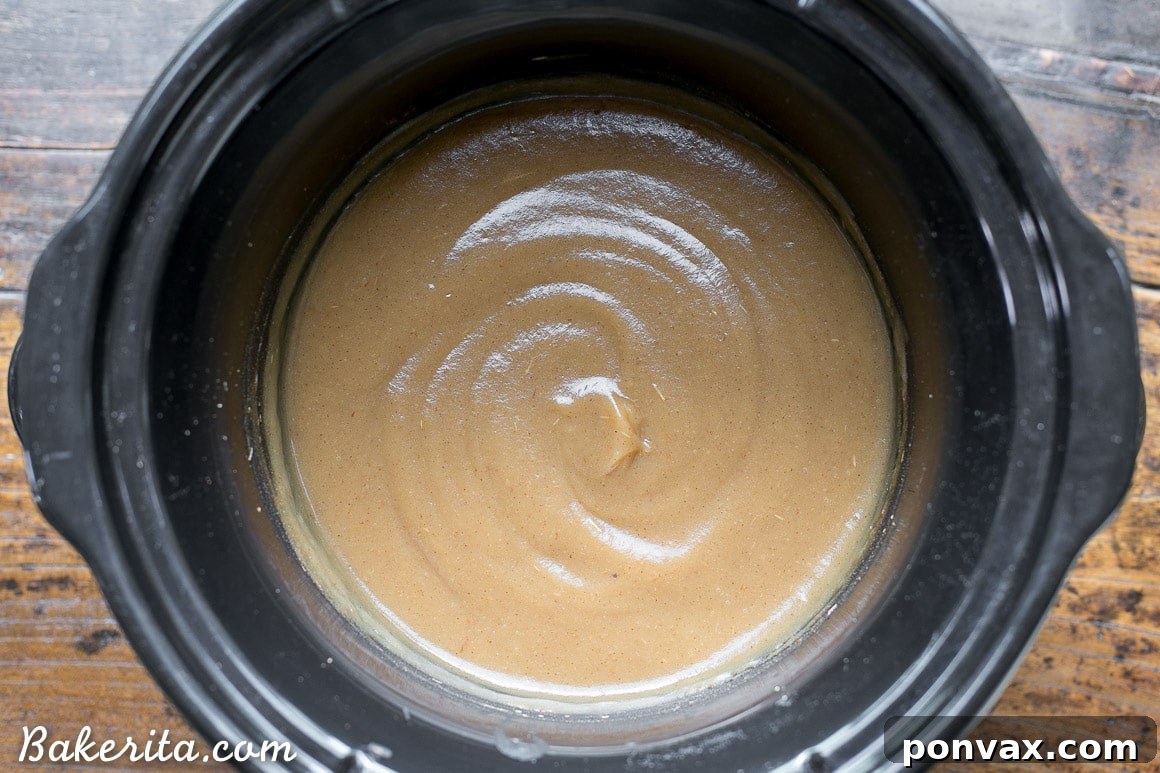 Naturally Sweet Slow Cooker Apple Butter 7 Blended, smooth apple butter in a slow cooker with cinnamon sticks, simmering to perfection.