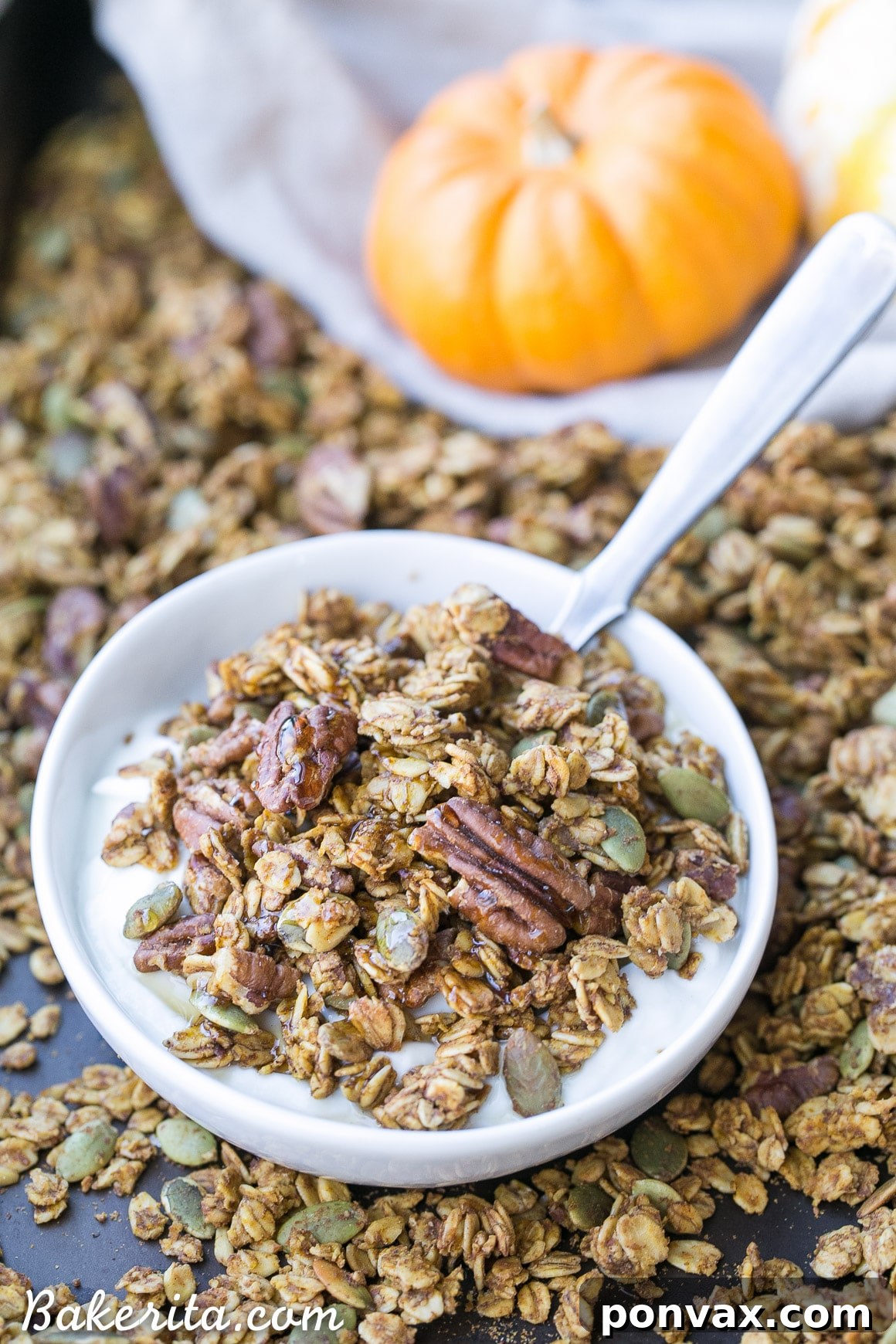 Freshly baked Pumpkin Granola scattered on a baking sheet, showcasing its golden-brown clusters and whole ingredients.