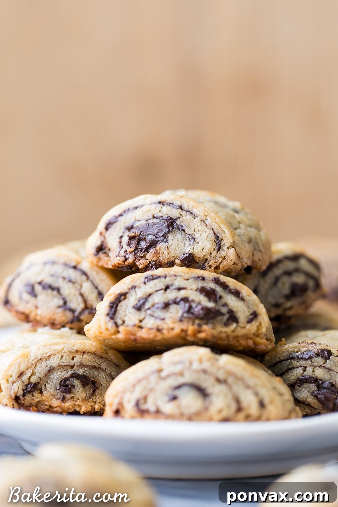 A close-up view of golden-brown gluten-free chocolate rugelach, featuring their distinctive rolled shape and a dusting of powdered sugar, ready for serving.