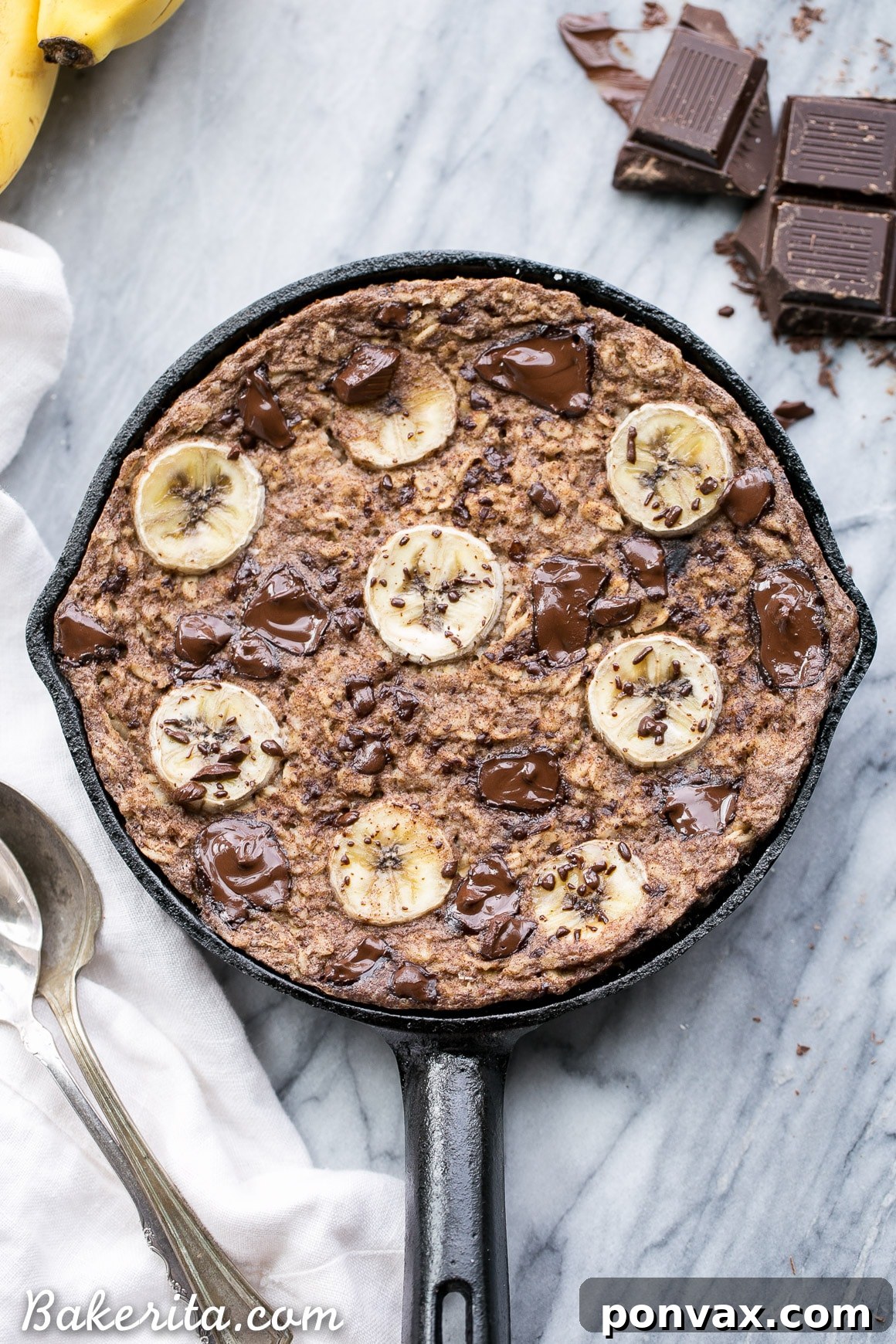 A close-up of freshly baked oatmeal cooling, showcasing the golden-brown, crispy crust and bubbling pockets of melted dark chocolate chunks.