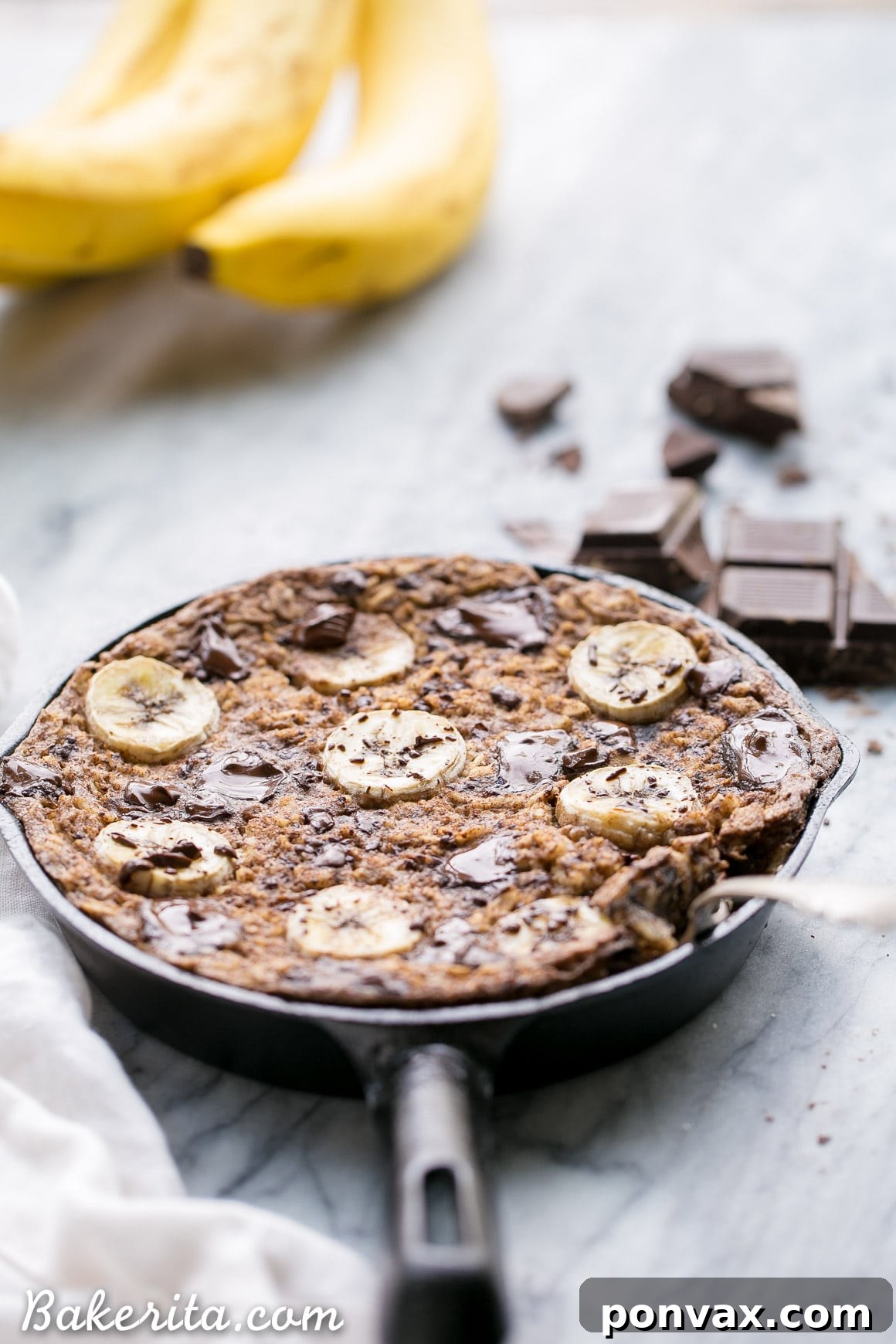 A close-up of a spoon scooping a portion of Chocolate Chunk Banana Baked Oatmeal, highlighting its soft, chocolatey interior and perfect texture.