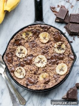 Delicious Chocolate Chunk Banana Baked Oatmeal ready to be served, topped with banana slices and melted chocolate.