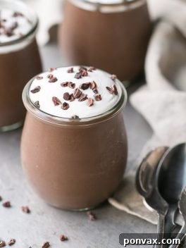 A beautifully presented bowl of homemade vegan chocolate pudding, garnished with fresh berries and mint.