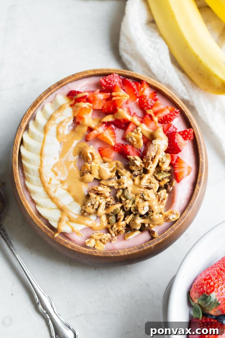 A person holding a bowl of Strawberry Banana Smoothie, showing its thick texture.