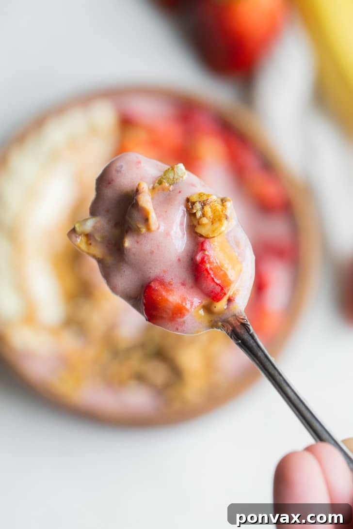 A beautifully decorated Strawberry Banana Smoothie Bowl with various toppings, ready to eat.