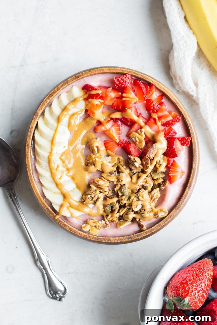 A close-up of a Strawberry Banana Smoothie Bowl showcasing various fresh fruit and seed toppings.