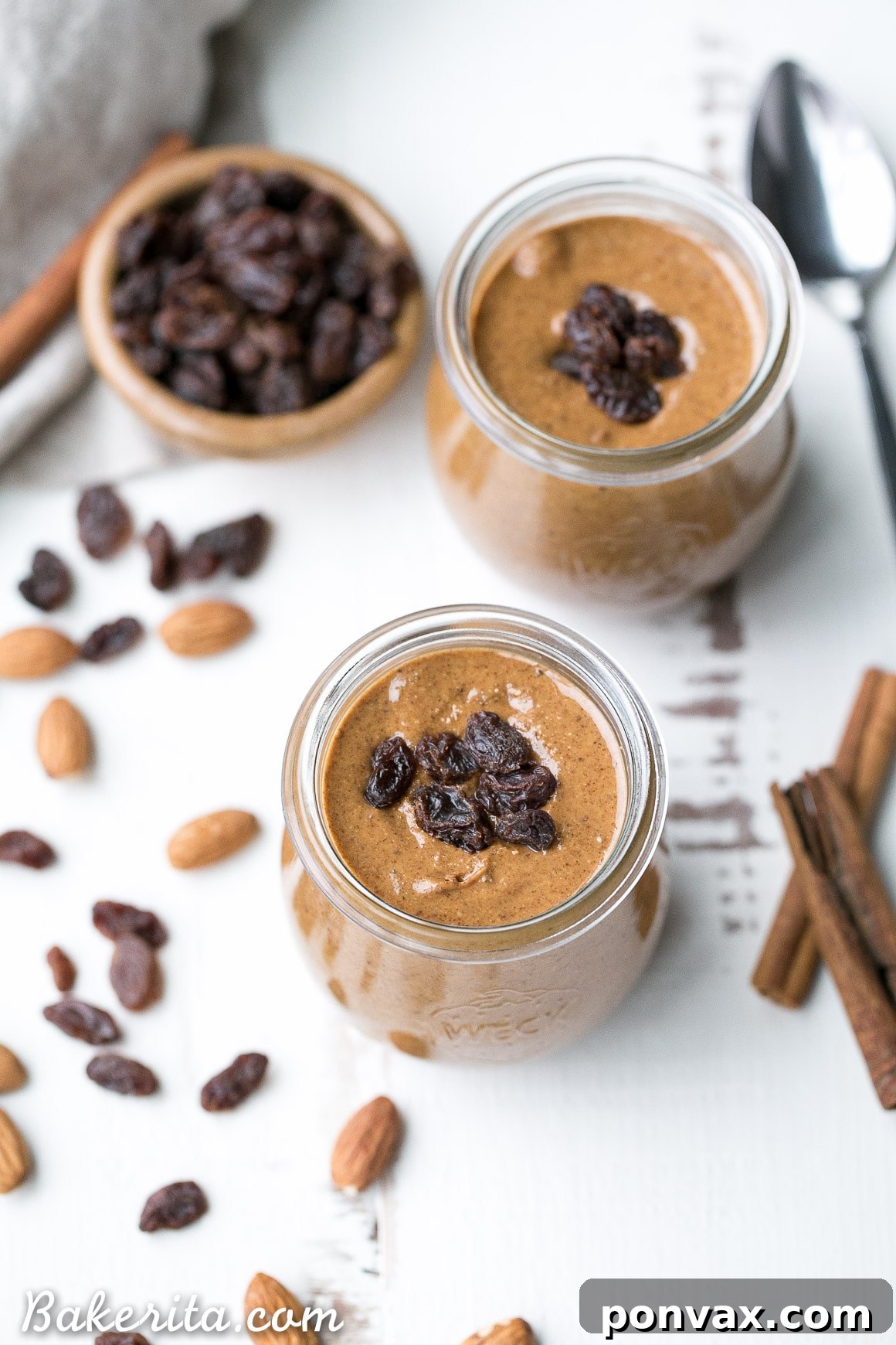 A spoon scooping creamy Cinnamon Raisin Almond Butter from a jar.