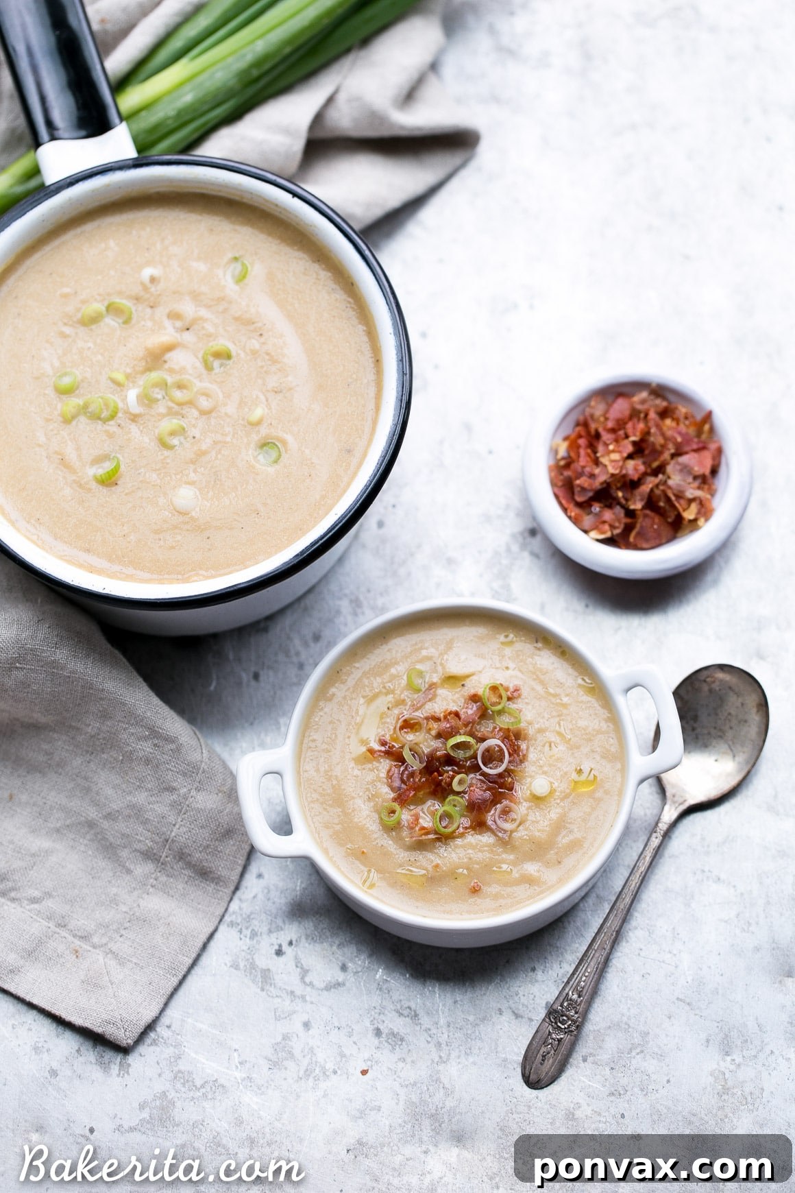 A ladle serving Cauliflower Leek Soup into a bowl, with garnishes nearby.