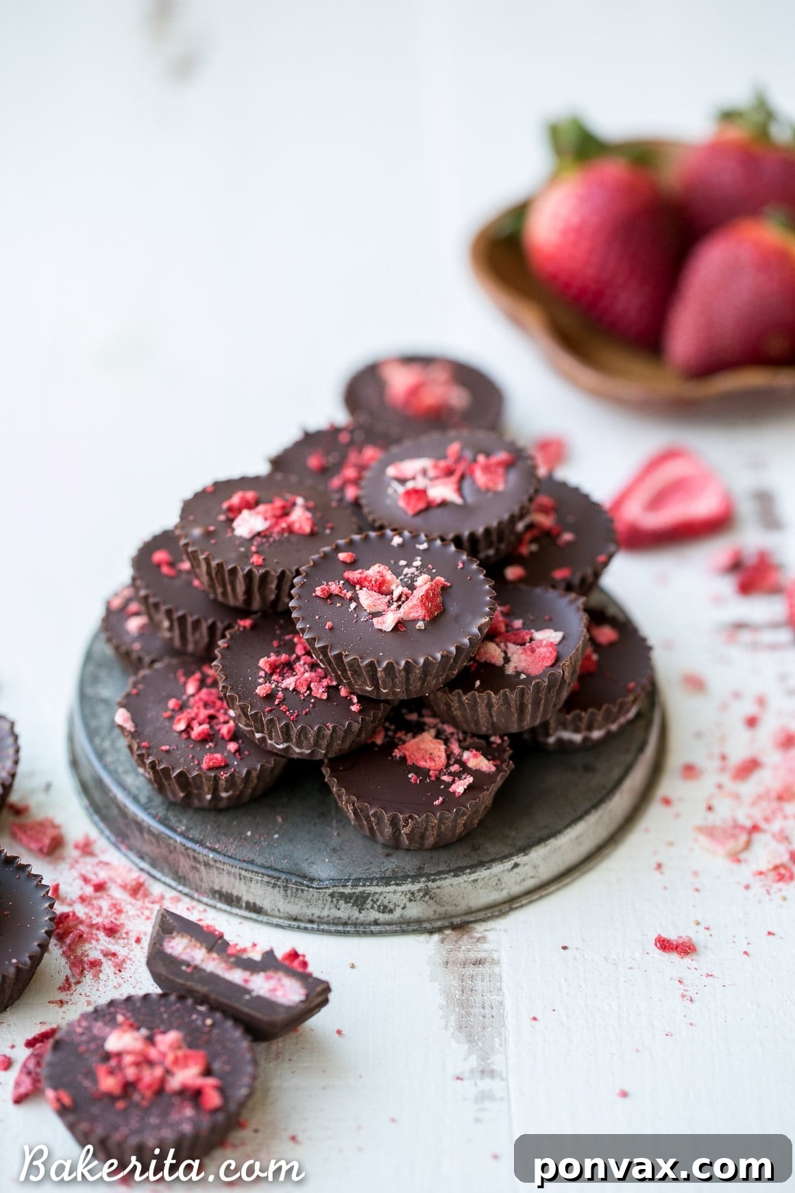 Delicious homemade chocolate strawberry cups with a creamy pink filling, garnished with freeze-dried strawberries. These are gluten-free, Paleo, and vegan.