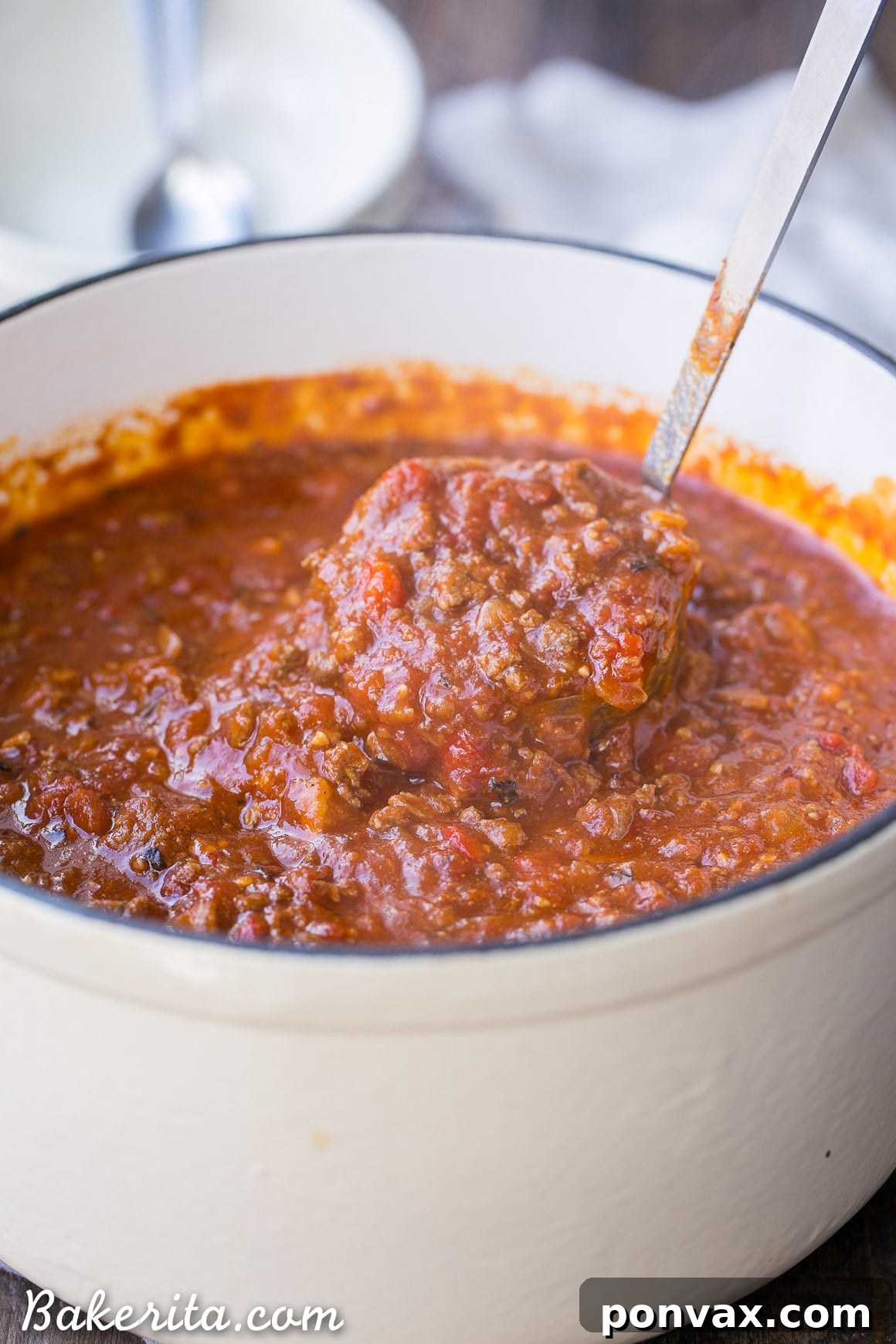 An overhead shot of a pot filled with simmering Low-Carb Paleo Chili, showing its robust texture and steam rising. The rich colors of the tomatoes, meat, and spices are evident, promising a flavorful dish.