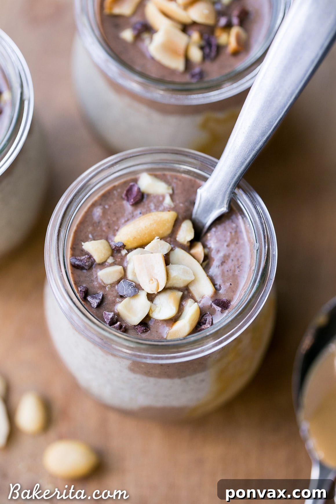 A close-up of a serving of Chocolate Peanut Butter Chia Pudding, garnished with chocolate chips and a spoon, highlighting its creamy layers and appealing texture.