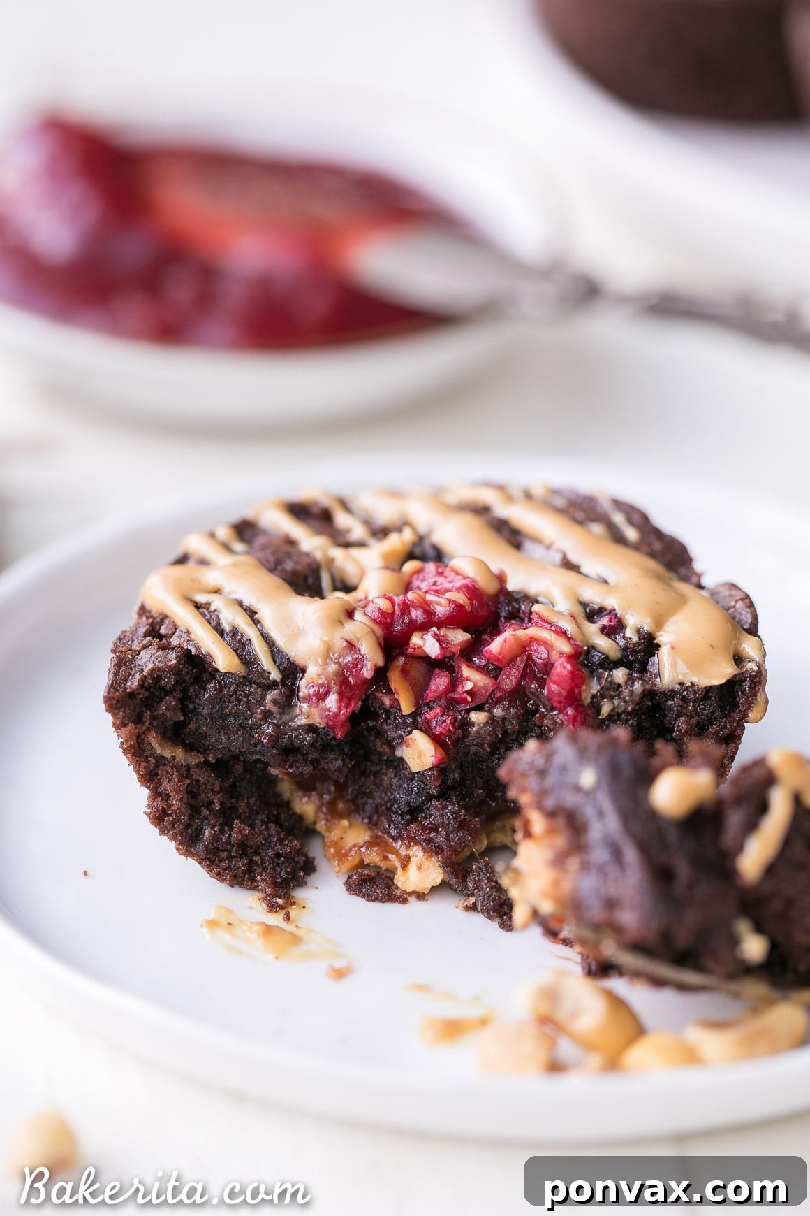Overhead shot of freshly baked gluten-free PB&J brownie bites in a muffin tin, garnished with fresh raspberries.