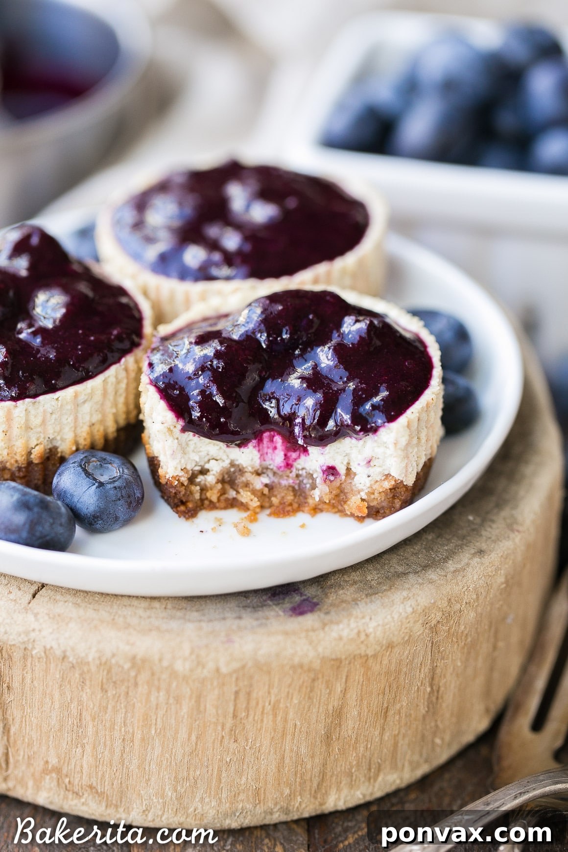 A vibrant close-up shot of a prepared Vanilla Bean Greek Yogurt Cheesecake, generously topped with glossy blueberry compote and adorned with a mint leaf, ready to be enjoyed.