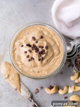 Heavenly Chocolate Chip Cookie Dough Nut Butter 8 Finished Chocolate Chip Cookie Dough Nut Butter in a jar, with a spoon nearby.