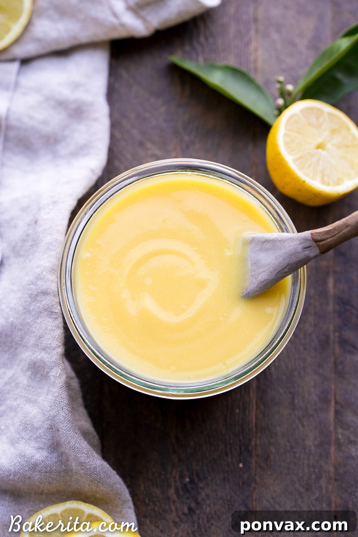 Paleo Lemon Curd being carefully poured from a saucepan through a fine-mesh sieve into a glass jar, ensuring a smooth, lump-free texture.