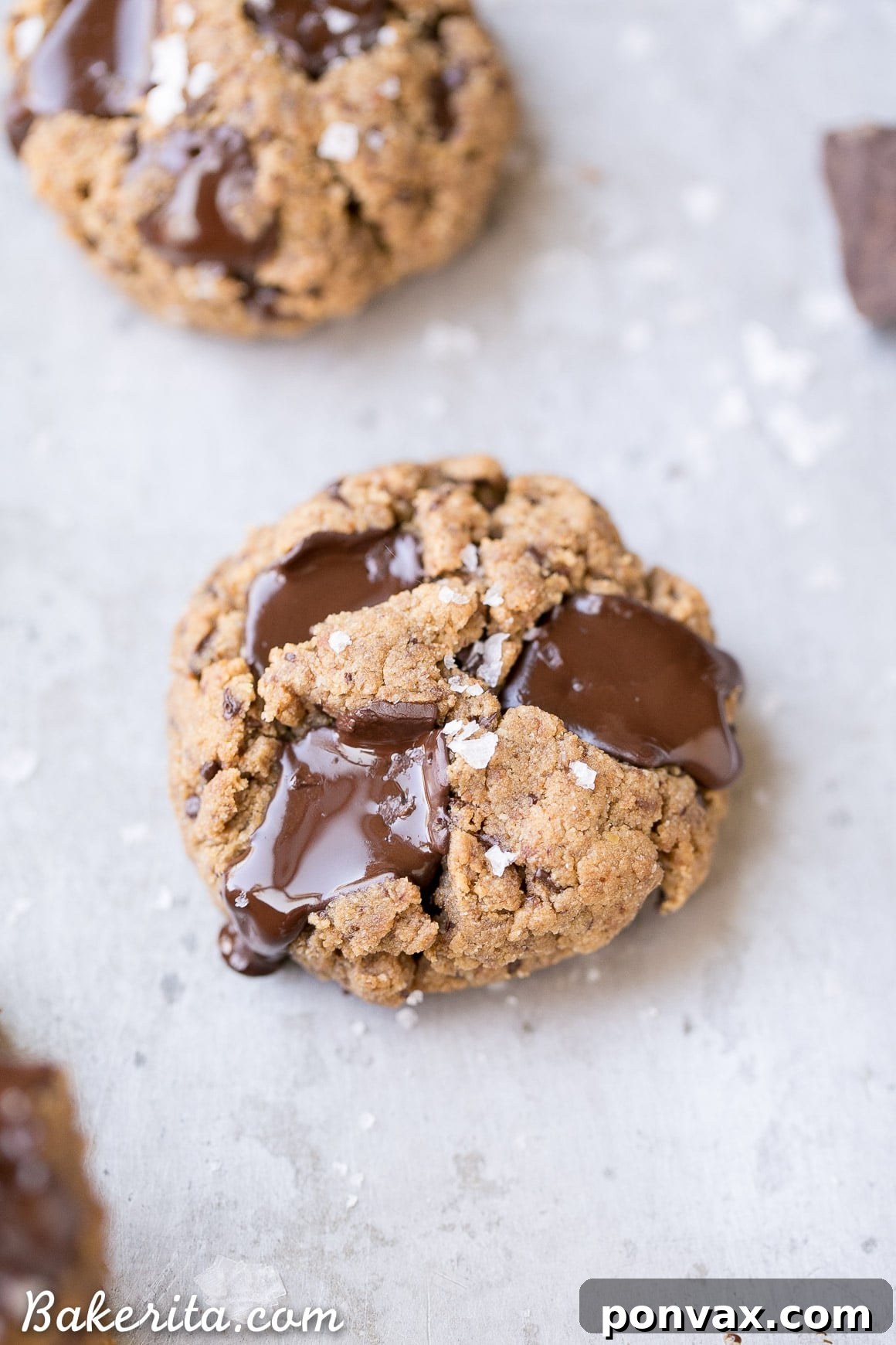 Two hands breaking a Gluten-Free Coconut Flour Chocolate Chip Cookie in half, revealing its soft, gooey interior and melted chocolate. A perfect vegan and Paleo treat.