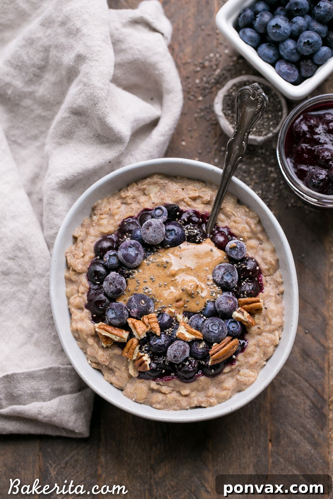 A bowl of creamy blueberry muffin oatmeal topped with fresh blueberries, nuts, and a drizzle of almond butter.