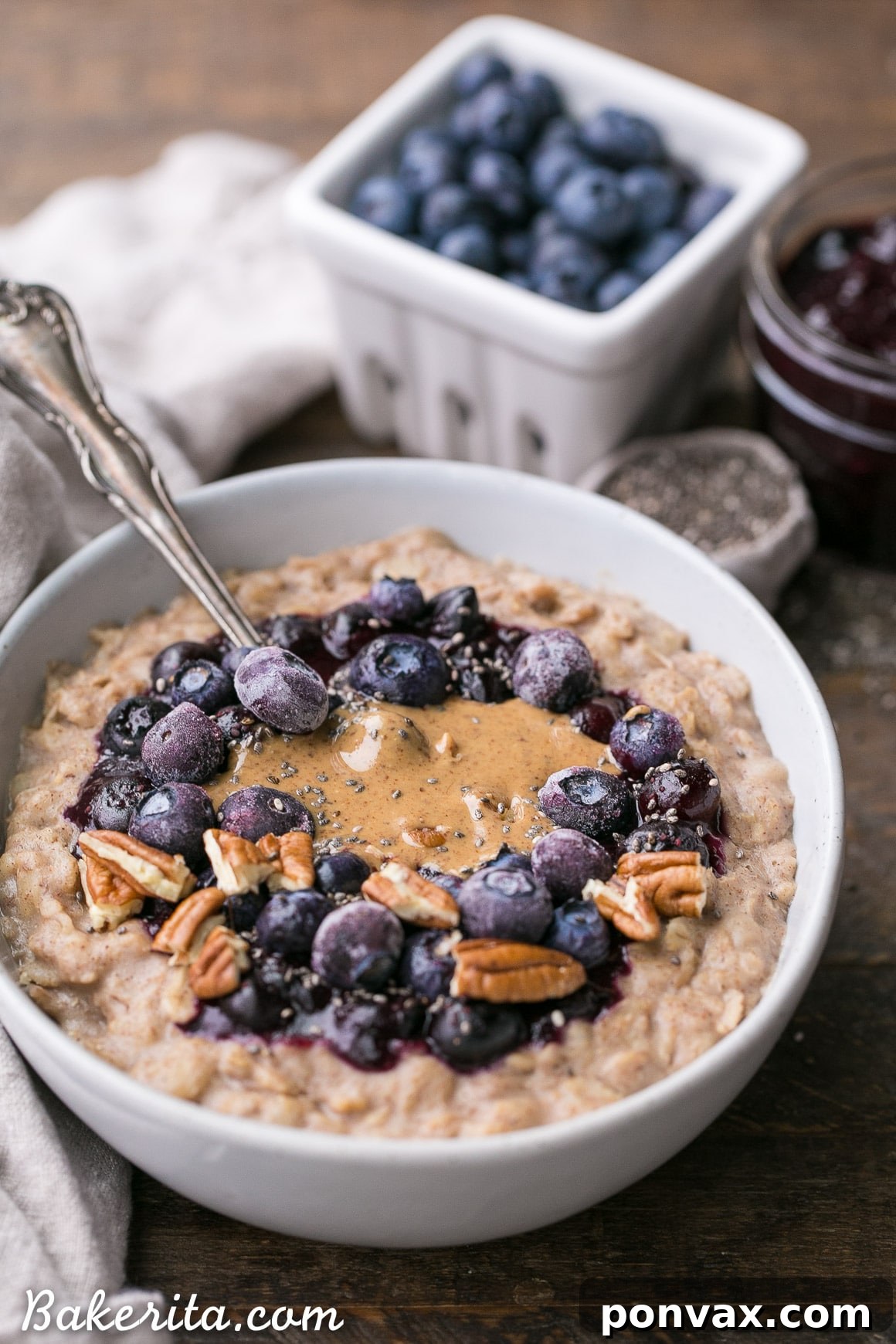 Overhead view of a vibrant bowl of blueberry muffin oatmeal, garnished with fresh fruit and seeds.